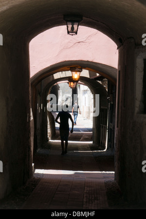 Deux jeunes hommes à pied à travers les ruelles sombres couverts à l'intérieur de la ville historique d'Albenga, Italie du nord Banque D'Images