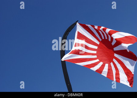 Drapeau japonais blowing in wind sur bleu azure sky avec pôle courbée Banque D'Images