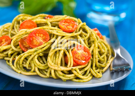 Spaghetti au pesto et tomates cerises cuit servi sur une plaque bleue Banque D'Images