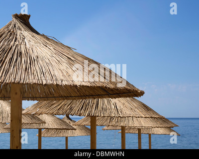 De nombreux parasols parasol de paille sur fond bleu ciel et la mer avec l'accent sur parasol avant Banque D'Images