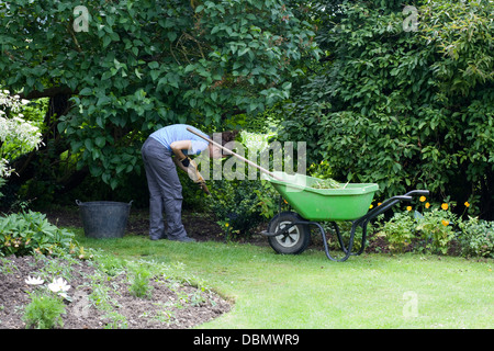 Dame avec Jardinage Brouette sur l'herbe à côté d'elle Banque D'Images