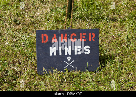 Panneau d'avertissement dans l'herbe noire "danger des mines, avec tête de mort Banque D'Images