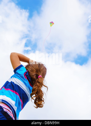 Petite fille à la recherche dans le ciel sur un magnifique cerf-volant coloré, vue arrière, profitant de l'été, jeu jouet volant, enfance heureuse Banque D'Images