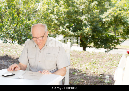 Portrait of Senior woman wearing eyeglasses en lisant le menu dans un restaurant en plein air, en été Banque D'Images