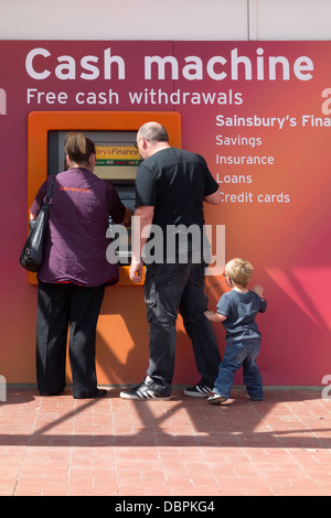 Homme Femme et enfant de retirer de l'argent dans un distributeur automatique Banque D'Images