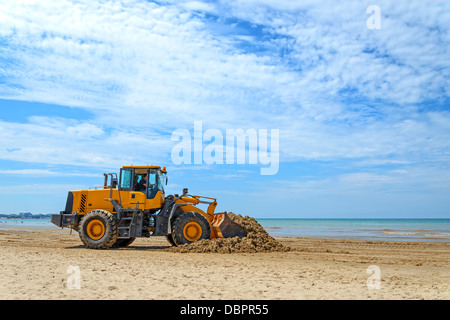 Le bulldozer Nettoie la saleté sur une plage après une tempête Banque D'Images