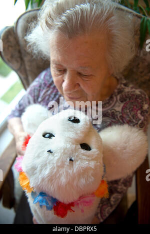 Helga Kollert (81) maintient le joint robot peluche 'Ole' se trouve sur une table à la maison de soins infirmiers pour les personnes atteintes de démence 'Haus O'land' à Brême, Allemagne, le 24 juillet 2013. Le robot est utilisé en ergothérapie avec les patients souffrant de démence. Il réagit au toucher et tourne la tête vers une voix en lui parlant. Photo : DAVID HECKER Banque D'Images