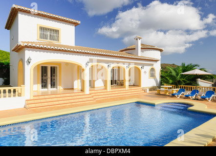 Une villa de vacances, remplir avec piscine, baigne dans le soleil espagnol tout en une série de nuages blancs moelleux passent par les frais généraux. Banque D'Images