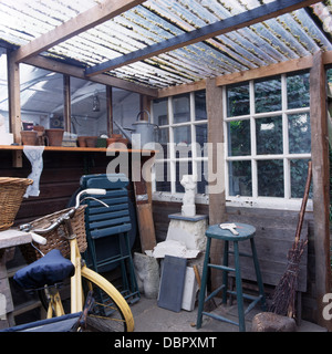 Ancien tabouret en bois peint en bleu et de vélos à l'intérieur de la remise de jardin avec toit en plastique ondulé Banque D'Images