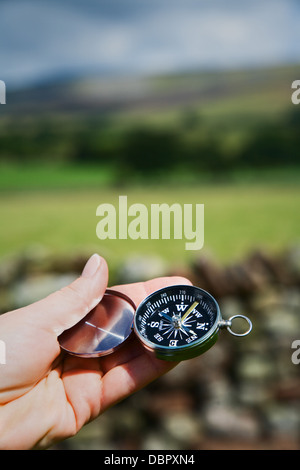 La main féminine détient jusqu'à établir l'orientation de la boussole. Banque D'Images