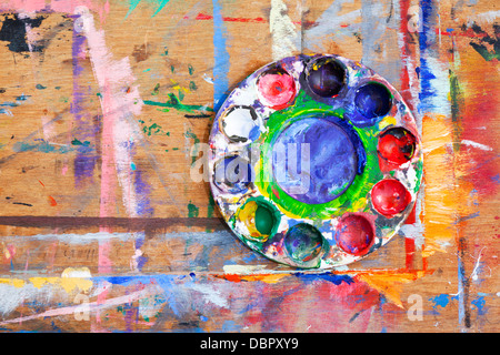 Close-up of a multi-couleur de peinture en plastique sur une planche de bois éclaboussé de peinture. Banque D'Images