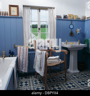 La langue bleue +rainure de murs en lambris et carrelage blanc +bleu en cottage salle de bains avec lavabo sur colonne et la vieille chaise en bois Banque D'Images