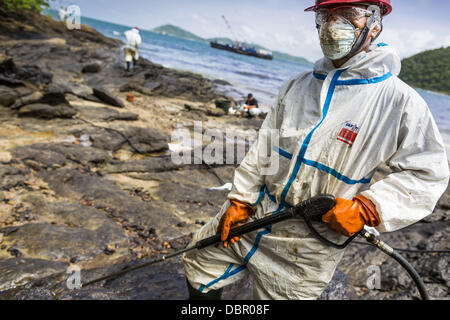 2 août 2013 - Koh Samet, Rayong, Thaïlande - un travailleur utilise un flexible haute pression à appliquer dispersant et à un déversement d'eau sur la plage d'Ao Prao. Environ 50 000 litres de pétrole brut déversé d'un pipeline dans le golfe de Thaïlande au cours de la semaine. Les travailleurs de la PTT, propriétaire du pipeline et jusqu'à 500 militaires thaïlandais et les bénévoles sont le nettoyage des plages. Chimique mondiale PTT PCL est contrôlée par l'État partie de PCL PTT, la plus grande société d'énergie de la Thaïlande. (Crédit Image : © Jack Kurtz/ZUMAPRESS.com) Banque D'Images