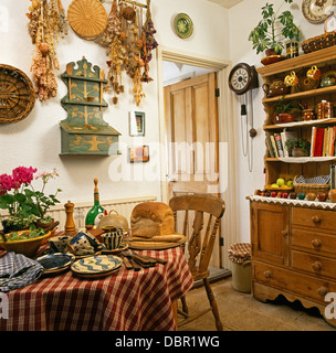 Tasses de poterie et les plaques sur la table avec un chiffon vérifié dans l'économie avec salle à manger vaisselier pin et rack avec fleurs séchées Banque D'Images