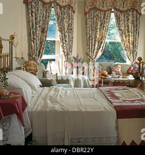 Dentelle Vintage parés de draps et d'arlequin sur laiton lit dans la chambre avec des rideaux Sanderson sur windows Banque D'Images