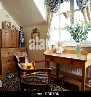 Lavabo en pin et vieille chaise avec siège rembourré leopard-print dans la fenêtre ci-dessous petite chambre mansardée avec tiger-tapis d'impression Banque D'Images