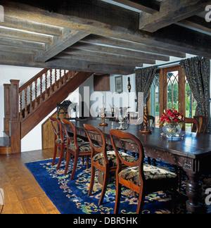 Retour par le ballonnet et chaises de style jacobéen dans table de salle à manger aux poutres apparentes dans la nouvelle maison de campagne de style Tudor Banque D'Images