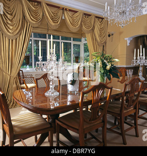 De style Regency table et chaises en pays salle à manger avec de la soie beige swagged +rideaux sur la fenêtre Queue Banque D'Images