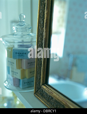 Close-up de miroir au cadre doré avec verre lidded pot plein de savons enveloppés Banque D'Images