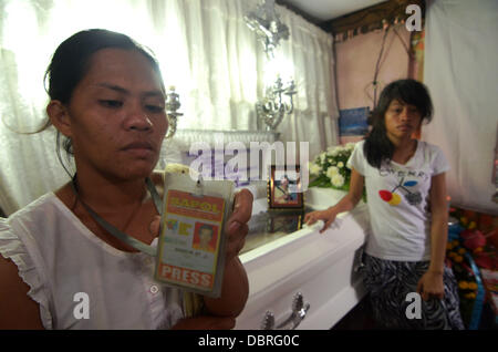 La ville de General Santos, Philippines du Sud. 3 Août, 2013. L'épouse de Mario Sy Violeta Sy (L) presse ID de mari Mario Sy comme ils pleurent après le corps de Mario Sy seulement arrivent dans leur chambre à midi à Santa Cruz Silway, General Santos City, Philippines du Sud, 03 août 2013. Offres news photographe Mario Sy a été tourné à l'intérieur de son domicile Vendredi, 01 août 2013. Sy a contribué à "photos de presse à l'APOL News Bulletin(Sur cible News Bulletin). Jubelag Sapol Editeur Jonh Paul a déclaré que la question des drogues illégales dans la zone Sy pourrait être le motif. Banque D'Images