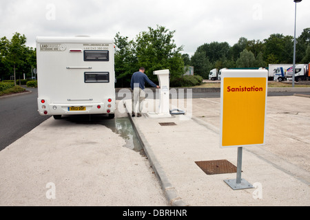 Un camping-car avec un camping à l'aide d'un flot Bleu 'Français' à un point de service aire sur une autoroute en France Banque D'Images