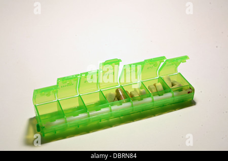Une couleur verte casemate hebdomadaire se trouve sur un fond blanc avec un assortiment de comprimés dans la boîte. Banque D'Images