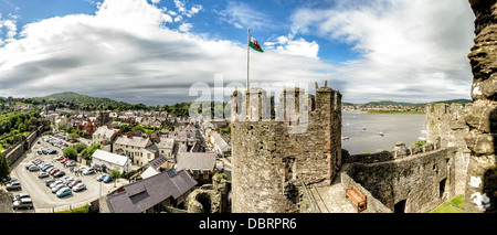 CONWY, pays de Galles — Une vue panoramique depuis les remparts du château de Conwy, une forteresse médiévale du XIIIe siècle dans le nord du pays de Galles, Royaume-Uni. La scène englobe certaines des tourelles imposantes du château au premier plan, avec la ville historique de Conwy et la rivière sinueuse Conwy visibles au loin. Ce site classé au patrimoine mondial de l'UNESCO, construit par le roi Édouard Ier, offre une vue imprenable sur le paysage environnant, mettant en valeur l'importance stratégique de son emplacement. Banque D'Images