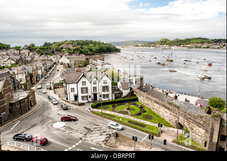 Château et ville de Conwy Pays de Galles | CONWY, Pays de Galles — La ville portuaire de Conwy s’étend le long de l’estuaire de la rivière Conwy, tel que vu depuis une tourelle du château de Conwy, ses rues en terrasses et ses bâtiments à pignons adossés aux collines de la péninsule de Creuddyn. Le château d’Édouard Ier et sa bourg fortifiée ont été construits ensemble à partir de 1283, avec une charte de 1284 restreignant le commerce de marché de la région à l’intérieur des murs de la ville. Banque D'Images