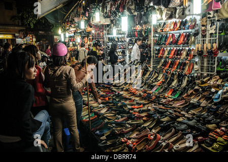 HANOI, Vietnam — les femmes vietnamiennes regardent les chaussures en vente dans un magasin de chaussures dans le vieux quartier de Hanoi. Banque D'Images