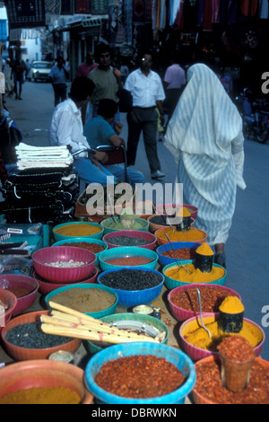 Épices sur un stand de rue avec une femme portant un haik blanc. Kairouan, Tunisie Banque D'Images