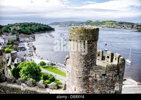 CONWY, pays de Galles — Une vue sur la rivière Conwy et le paysage environnant vus depuis les tourelles du château de Conwy, une forteresse médiévale du XIIIe siècle dans le nord du pays de Galles. Le premier plan présente quelques-uns des remparts et tourelles bien conservés du château, soulignant l'impressionnante architecture défensive de ce site classé au patrimoine mondial de l'UNESCO. Construit par le roi Édouard Ier lors de sa conquête du pays de Galles, le château de Conwy offre aux visiteurs une vue panoramique sur la ville et l'estuaire en contrebas. Banque D'Images