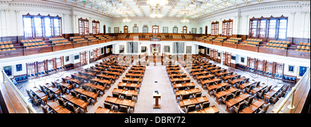 Texas State Capitol House of Representatives Chamber Panorama Austin / AUSTIN, Texas — Une vue panoramique cousue de la chambre de la Chambre des représentants du Texas dans le Texas State Capitol montre l'étendue complète de l'étage de 150 places, la galerie publique à deux niveaux et le plafond orné de fer peint au-dessus. Contrairement au Congrès américain, la législature du Texas se réunit en session ordinaire seulement tous les deux ans, limitant les législateurs à 140 jours – une contrainte qui compresse l’ensemble du cycle budgétaire de l’État en un seul sprint biennal. Il s'agit d'une image panoramique Assemblée, une capture multi-images, haute résolution. Banque D'Images