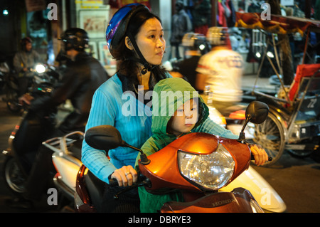 HANOI, Vietnam — Une mère et sa fille conduisent un scooter dans une rue animée du vieux quartier du centre-ville de Hanoi. Banque D'Images