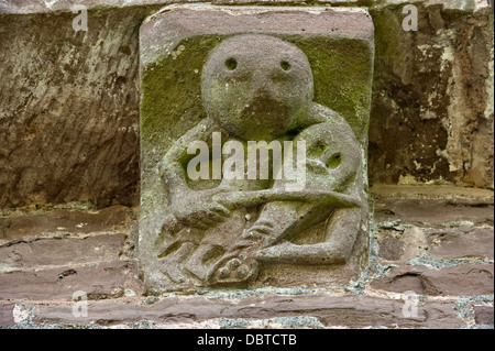 Un corbel en pierre sculptée montrant un musicien jouant un violon, sur l'ancienne église de St Mary & St David, Kilpeck, Herefordshire, Royaume-Uni, construite vers 1140 Banque D'Images