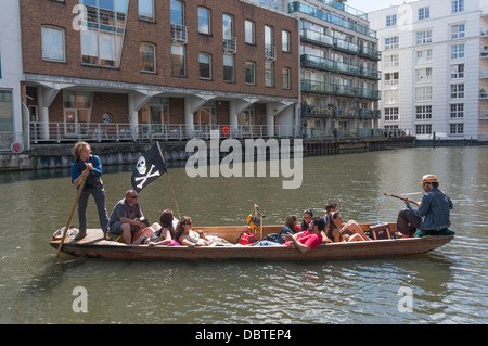 Un punt bateau avec les touristes à bord et un guitariste, à Camden Lock, près de Camden Market, Londres, Angleterre, Royaume-Uni. Banque D'Images