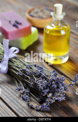 L'huile essentielle de lavande, savon à base de plantes et bouquet de fleurs de lavande sur fond de bois. Banque D'Images