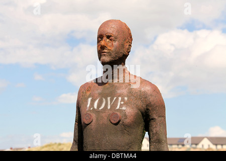 Amour écrit sur l'une des statues Antony Gormley a appelé un autre lieu à Crosby Beach. Banque D'Images