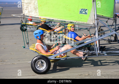 Les personnes conduisant le char à voile sur la plage. Ils sont en train d'apprendre et d'avoir du plaisir. 4 Hommes roulant côte à côte à l'avant-plan. Banque D'Images