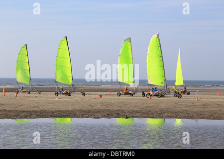 Les personnes conduisant le char à voile sur la plage. Ils sont en train d'apprendre et d'avoir du plaisir. Réflexions de la voile coloré sur l'eau Banque D'Images