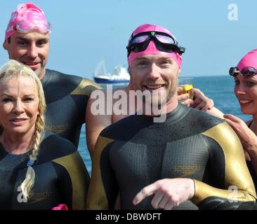 Singer Ronan Keating, les présentateurs de télévision Jenny Frost et Jason Bradbury, et strictement star Pamela Stephenson ont terminé un marathon de natation de collecte de fonds à travers la mer d'Irlande. La nageuse médaillée olympique dirigée par Steve Parry, ils ont tous touché terre sur une plage à ni Banque D'Images