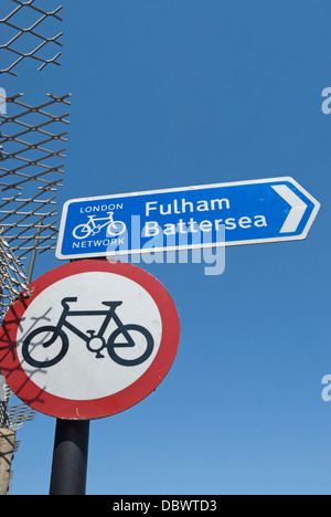 Panneau routier indiquant pas de vélo à côté d'une randonnée à vélo signer avec des directions pour Fulham et Battersea, dans Wandsworth, Londres, Angleterre Banque D'Images