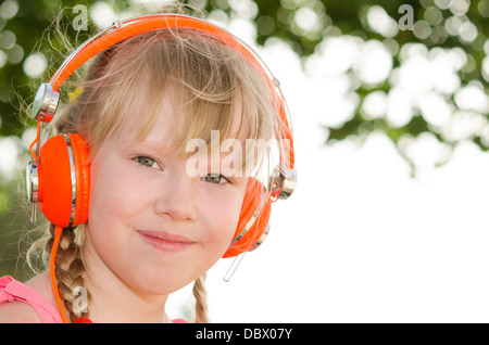 Closeup portrait of cheerful girl l'écoute au casque leçon contre l'arrière-plan flou vert blanc Banque D'Images