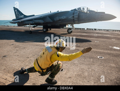 L'Aviation de l'US Navy un maître de Manœuvre signale le pilote d'un Harrier AV-8B fighter jet qu'il est autorisé à lancer depuis la cabine de pilotage du navire d'assaut amphibie USS Bonhomme Richard le 4 août 2013 dans la mer d'Oman. Banque D'Images