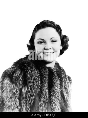 Années 1930 Années 1940 YOUNG SMILING WOMAN WEARING FUR COAT LOOKING AT CAMERA Banque D'Images