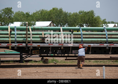 Un travailleur obtient une charge de tuyau sur son camion pour une utilisation dans l'Eagle Ford Shale, une zone d'intense production pétrolière et gazière. Banque D'Images