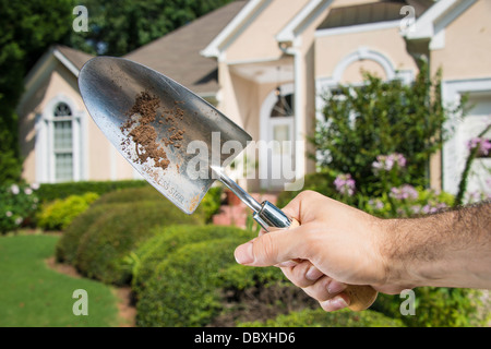 Man's hand holding sale chat jardinage en face d'une pelouse devant la maison. Banque D'Images