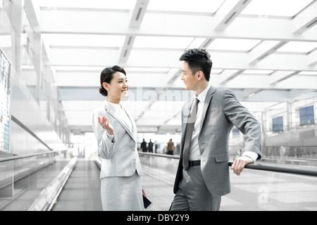 Des collègues ayant la conversation sur l'escalator de l'aéroport Banque D'Images