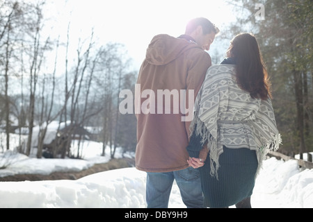 Couple holding hands and walking in snowy lane Banque D'Images