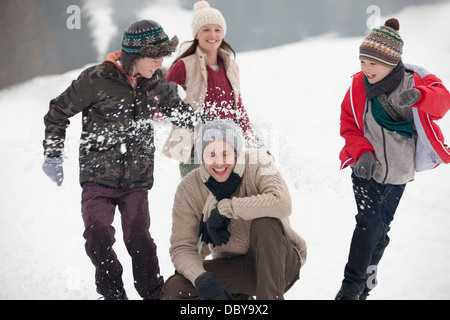 En famille ludique snowball fight in field Banque D'Images