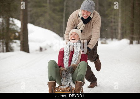 Heureux couple Sledding in snowy field Banque D'Images